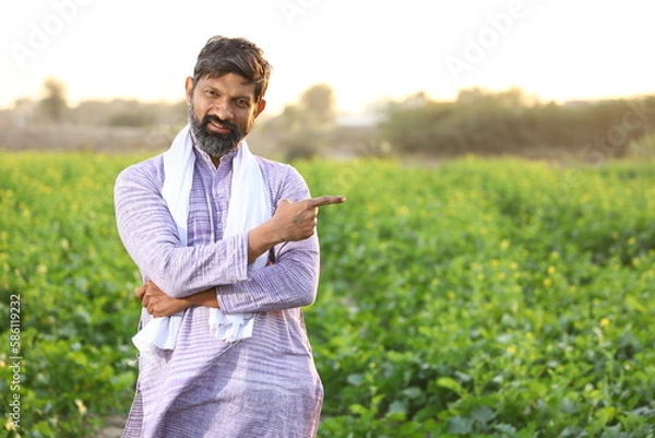 Obraz Happy rural Indian a farmer pointing at his right side while looking at the camera.