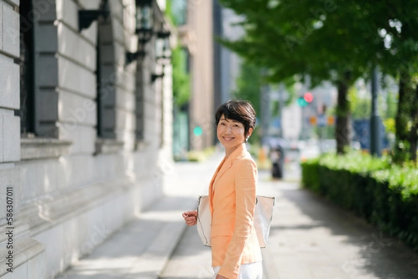 Fototapeta オフィス街を歩くミドルエイジのビジネスウーマン