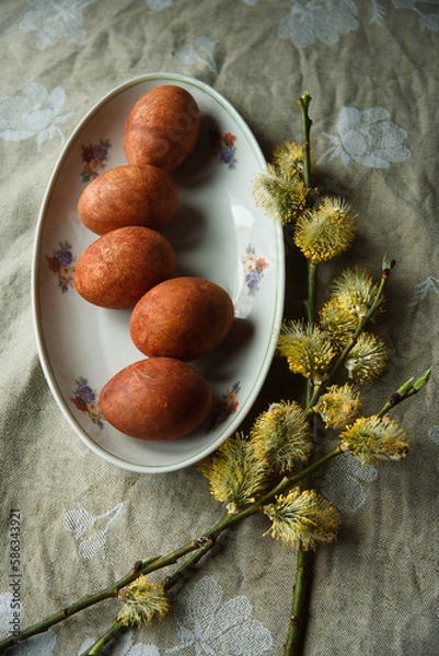 Fototapeta Happy Easter! Easter naturally painted orange eggs on plate with flowering willow tree branches on rustic table.