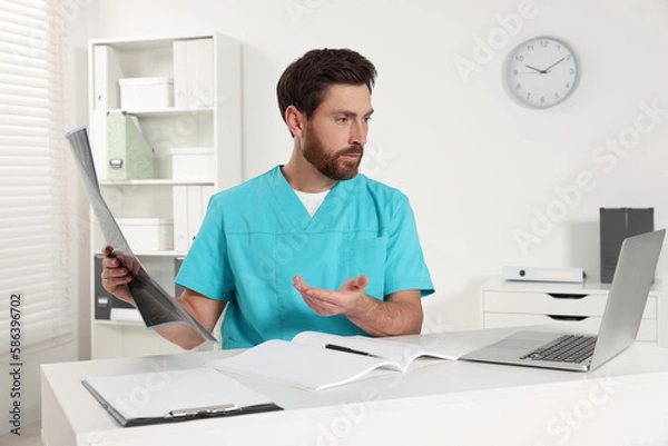 Fototapeta Doctor explaining MRI scan by videochat in hospital