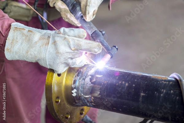 Fototapeta Hands welding a metal pipe
