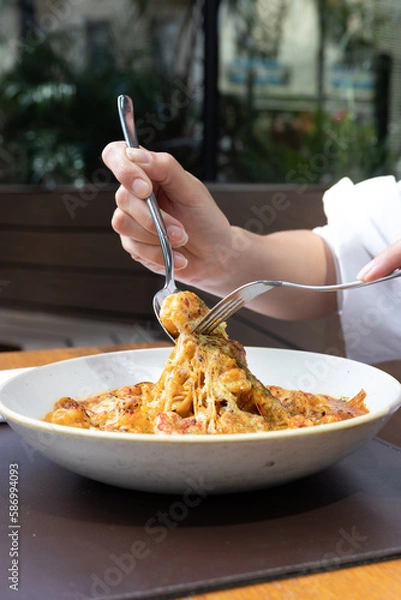 Fototapeta Manos levantando pasta con salsa de camarones y queso fundido,