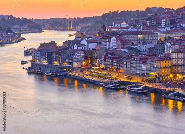Fototapeta Sunset over the Douro river seen from the Jardim do Morro, a verdant hillside area, accessible by cable car, with benches and a grove of trees and palms at the top, Porto, Portogallo
