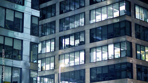 Fototapeta Pattern of office buildings windows illuminated at night. Glass architecture ,corporate building at night - business concept. Blue graphic filter.