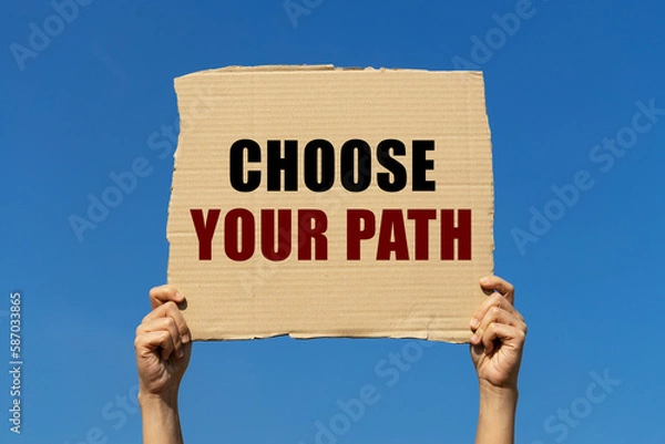 Obraz Choose your path text on box paper held by 2 hands with isolated blue sky background. This message board can be used as business concept about choosing your path.
