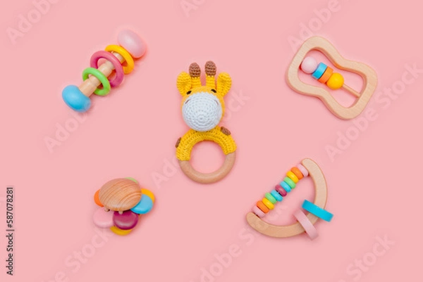 Obraz Cute set of wooden rattles for baby on pink background. Eco-friendly toys for newborns in the colors of the rainbow. Flat lay.