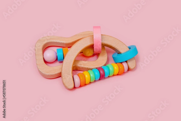 Obraz Wooden rattles for baby on a light pink background. Eco-friendly toys for newborns in the colors of the rainbow. Flat lay, copy space.