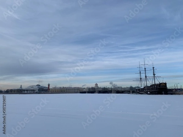 Obraz View from the Mytninskaya embankment to the ice-covered Neva, the Spit of Vasilevsky Island, the Rostral columns and the ship. Against the background of the sky with beautiful clouds in St. Petersburg