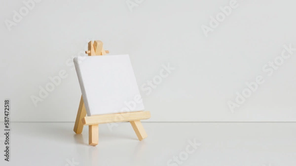 Fototapeta Mini painting on an easel on a light background. at an angle