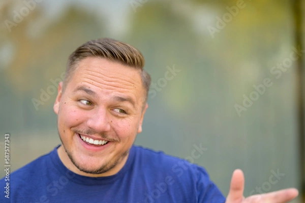 Fototapeta Teasingly smiling young man pointing at someone