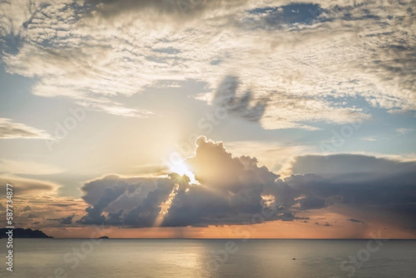 Obraz Spectacular sunrise with the sun through the clouds on the sea. Sun reflecting in the clouds. Sunbeams cast shadow on the cloud. 