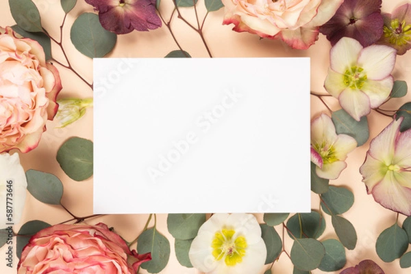 Fototapeta Stationery flat lay with a blank invitation card and fresh rose flowers on a blush cream background