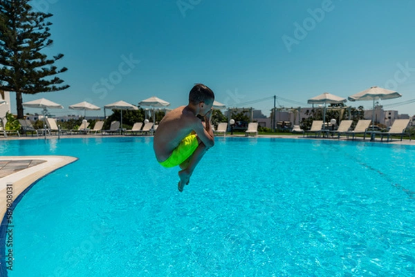Fototapeta Naxos, Grece - July 20, 2020 - Boy jumping to the pool in the small family hotel on Naxos Island