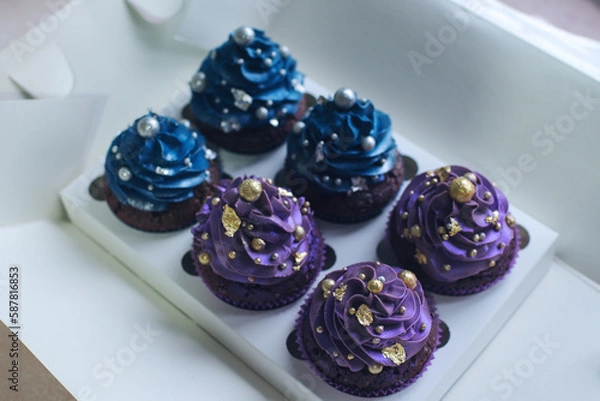 Obraz Set of chocolate cupcakes with dark blue and purple cream and golden sprinkles