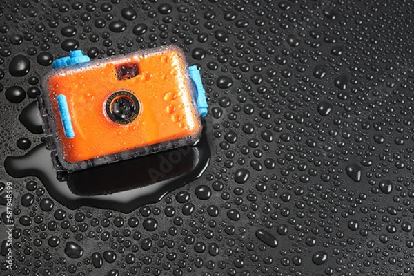 Fototapeta orange pocket camera or  film camera in waterproof case with water drop on black background with copy space