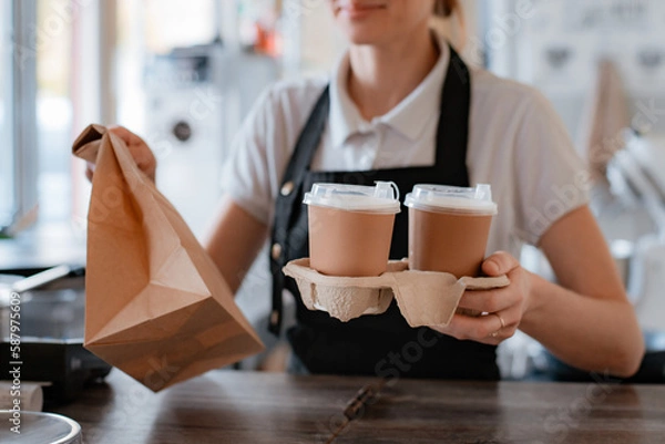 Fototapeta Buying fast food. A pancake with filling and a paper cup with coffee in the hands of a woman seller and a customer in the cafeteria. Takeaway food.