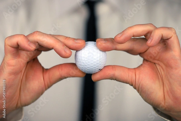 Obraz A businessman in a white shirt and black tie holding golf ball in his hands.