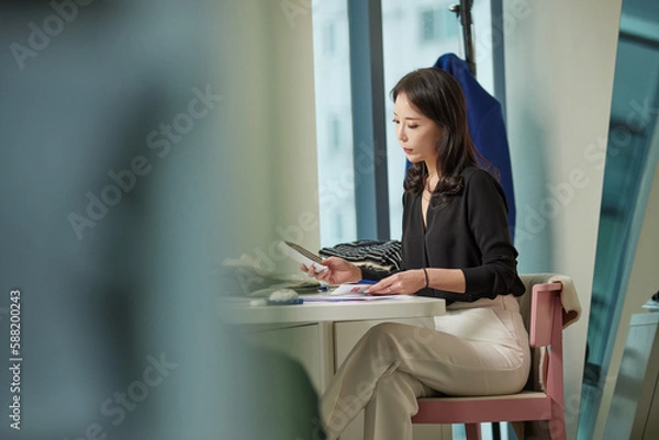 Obraz 사무실에서 다리를 꼬고 앉아있는 젊은 여성