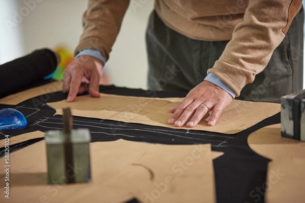 Fototapeta 밑그림을 그린 원단에 패턴지를 올리고 작업하는 재단사의 손 