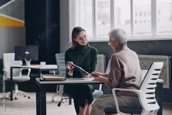 Obraz Senior woman having a meeting with financial advisor while sitting in the office together