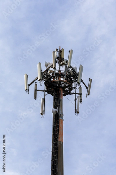 Fototapeta close-up view of a cellphone and internet 5G antenna with overcast sky copy space
