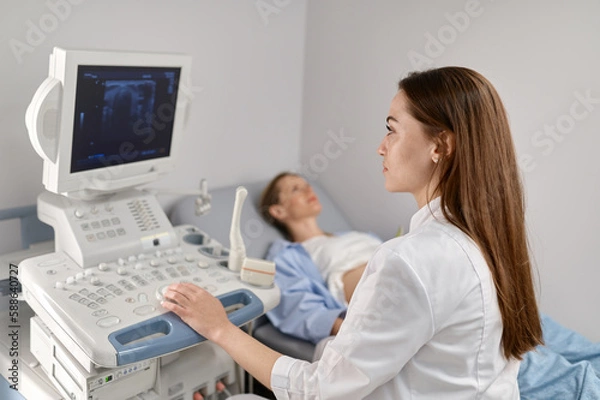 Fototapeta Selective focus doctor doing ultrasound of fetus to pregnant woman