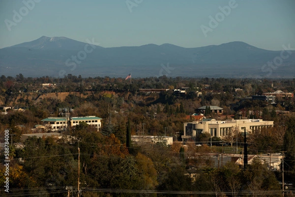 Fototapeta Redding, California, USA - November 22, 2021: Late afternoon sun shines on downtown Redding skyline with a mountain backdrop.