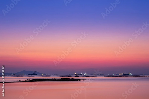 Fototapeta long exposure technic therefore motion blurred effect Smoky and soft sea water surface with small island named Koh Loy boat  rock and commercial vessel container cargo at horizon during sun set