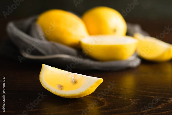 Fototapeta Lemons in a vegetable grid on a dark background. Slice of juicy lemon macro