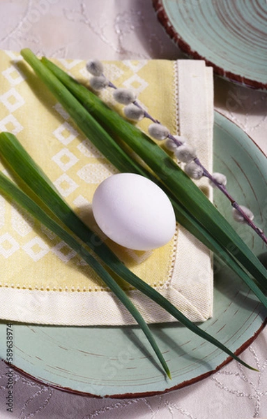 Fototapeta Easter table setting with green leaves, willow branch and white egg on green plate.