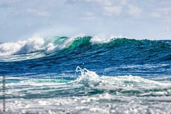 Fototapeta White foamy splashing waves on the beach