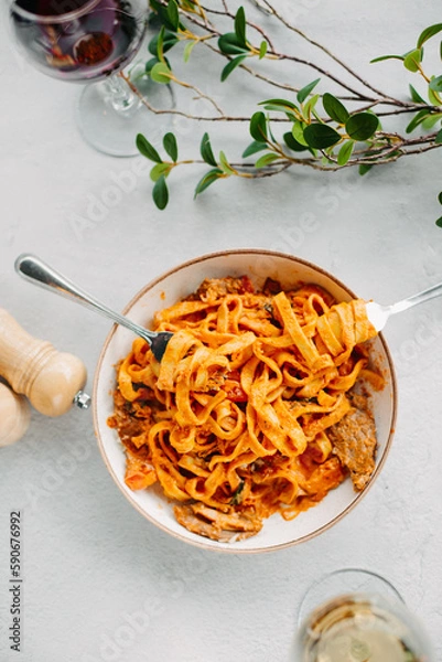Fototapeta Pasta bavette with fried shrimps, bechamel sauce. Woman hands in frame, girl eats pasta, holds fork in hands, top view, italian cuisine.