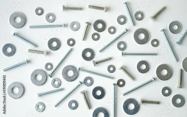 Obraz Close-up bolts, nuts and washers are scattered in a chaotic manner on a white background.  Flat lay top view, close-up.  Background with metallic elements.