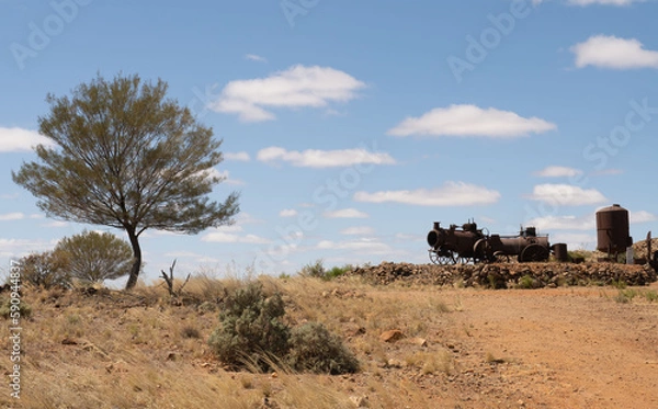Fototapeta Desert scene near Silverton, New South Wales, Australia. Old rusty steam engine and boiler previously used for mining and mulga trees.