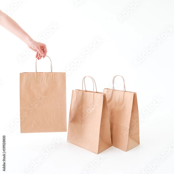 Fototapeta The hand reaches for a craft bag on a white background. Space for text and logo. The concept of packaging, delivery, shopping, food.