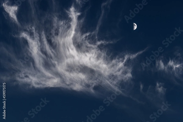 Fototapeta A crescent moon against a dark blue sky and a white cloud