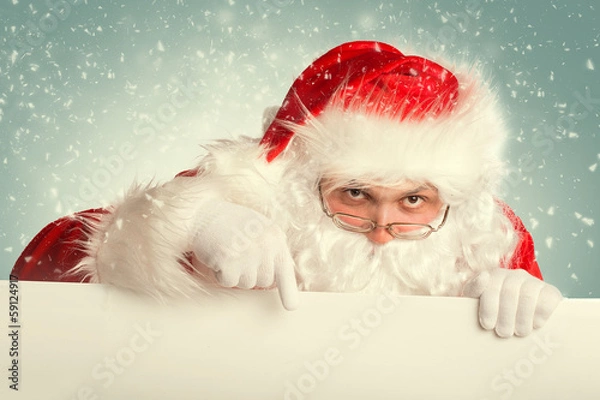 Fototapeta Santa Claus in a snow pointing to white blank banner