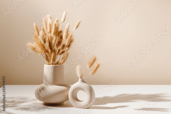 Fototapeta Stylowy wazon ceramiczny ustawiony na stole z suszonym bukietem trawy Lagurus z cieniami, jasnobrązowe tło ściany. Wazon skandynawski na stole z przestrzenią kopiowania, minimalna estetyczna dekoracja wnętrza