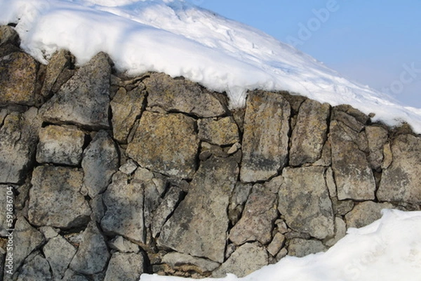 Obraz Old stone wall or rock covered by snow