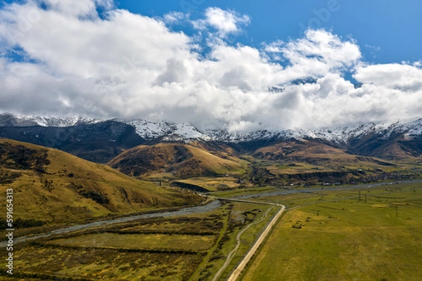Fototapeta breathtaking view of snow-capped mountains from a drone in summer