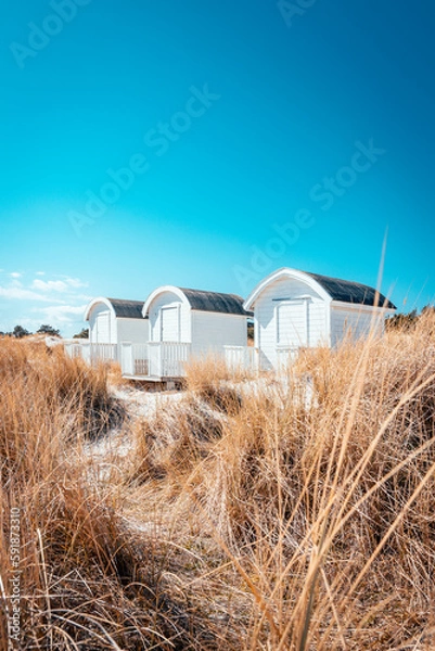 Obraz Three white beach huts sitting on the beautiful sand dunes in Falsterbo on the south western tip of Sweden. Selective focus.