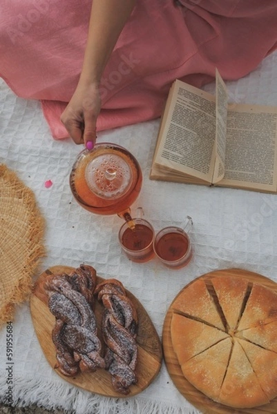 Obraz Picnic in spring under a tree in nature. A gourmet picnic in the park, laid out on a carpet around wine, cheese, fresh fruit, croissants.