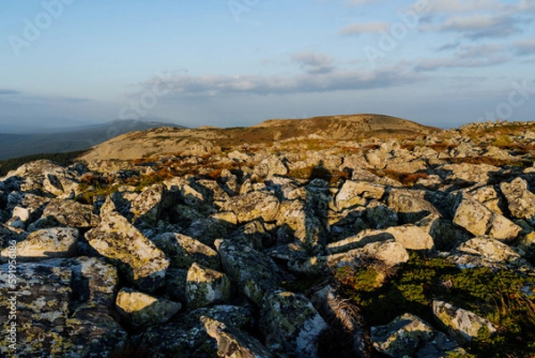 Fototapeta The shadow of a man against the background of stones, a mountain trip alone, a tourist meets the dawn on the mountain, large stones, a flat top.