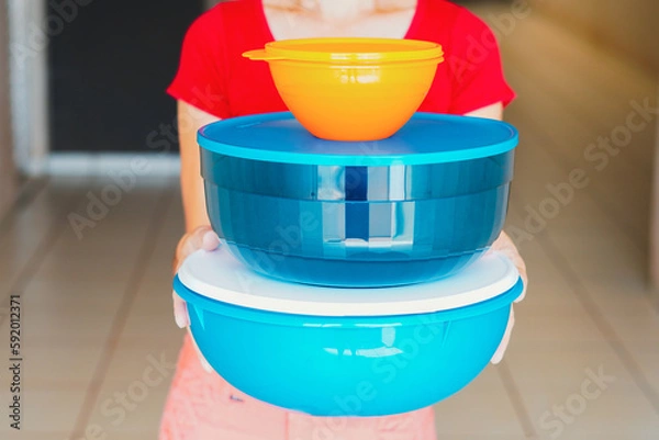 Fototapeta Aerson carries a pile of plastic Tupperware containers. The company recently admitted it could go bankrupt.
