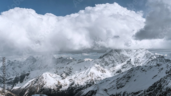 Obraz Alpine landscape with peaks covered with snow and clouds