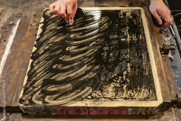 Fototapeta The artist is cleaning a Lithographic limestone with a clotch and chemicals in an art workshop.