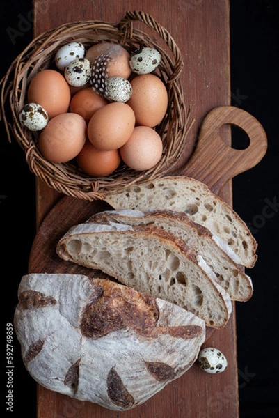 Fototapeta Sliced handmade bread and a basket of chicken and quail eggs.