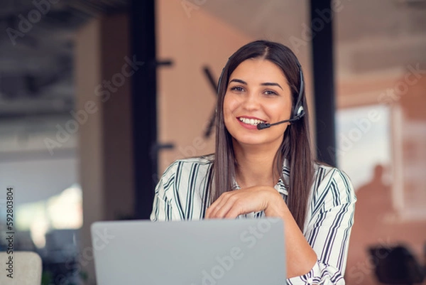 Fototapeta Young friendly operator woman agent with headsets working in a call centre.