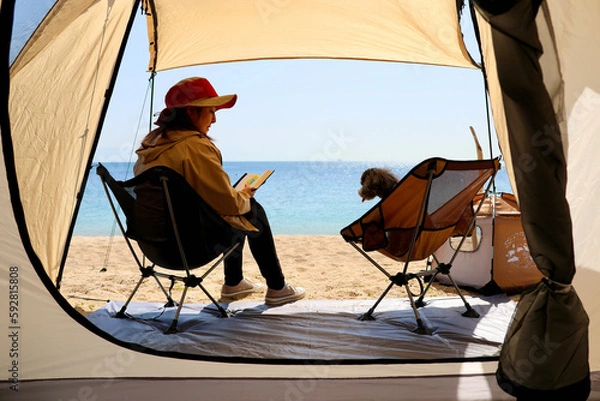 Fototapeta トイプードルを連れて女子キャンプ　青い海・美しいビーチでのんびり島キャンプ　キャンプ料理や愛犬と休日を楽しむ女性　海の見えるキャンプ