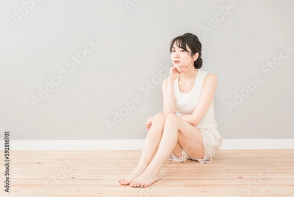 Obraz フローリングに座って頬杖をついて考える・悩む女性（美容・スキンケア・ダイエット）
